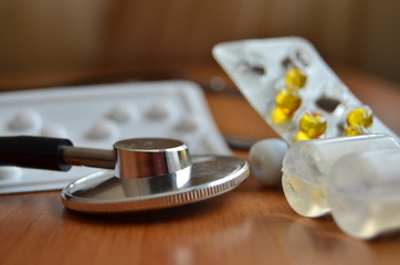 Stethoscope and bunch of used pills close up. Soft focus