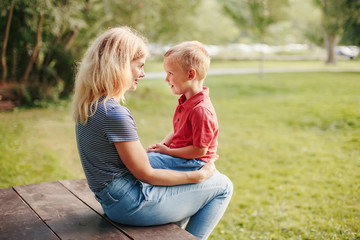 Young Caucasian mother and boy toddler son sitting together face to face. Family mom and child...