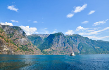 Small ferry exploring beautiful fjord Sognefjord with rocky shores and turquoise water. Cruise around scandinavian beauty. Norway