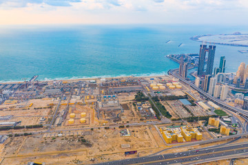 Aerial view of petrochemical oil refinery and sea in industrial engineering and energy concept in Dubai, urban city, UAE. Oil and gas tanks pipelines in industry. Modern metal factory. Power plant.