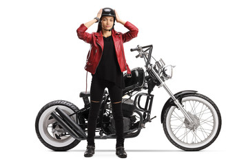 Fototapeta na wymiar Young female biker standing and putting on a helmet next to a chopper motorbike