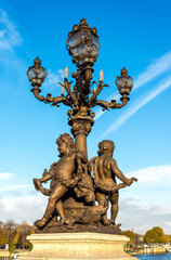 Fototapeta na wymiar Scenic ornate light post with nymphs of the Neva sculpture group on the Alexander III bridge, Paris, France. Sculptor: Georges Recipon (1860-1920)