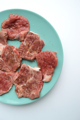 Pieces of meat ready for marinade lying on a plate with spices