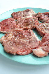 Pieces of meat ready for marinade lying on a plate with spices