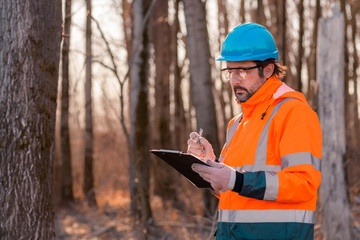 Forestry technician writing notes on clipboard notepad paper in forest