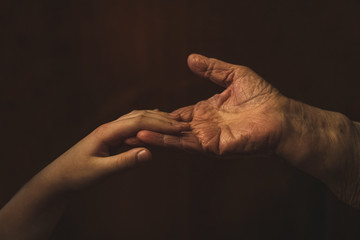 Human hands wrinkled adult senior and child holding each other. Bonding a great-grandmother and...