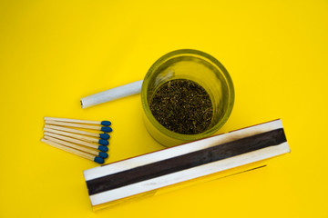 Marijuana cigar and matches on a yellow background, zenith