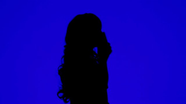 Silhouette of a woman talking on a cell phone on a blue background