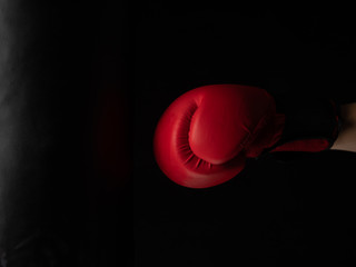 red boxing glove hitting the punching bag on black background