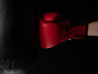 red boxing glove hitting the punching bag on black background