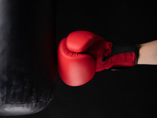 red boxing glove hitting the punching bag on black background
