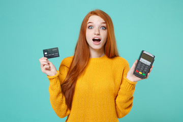 Shocked redhead girl in yellow sweater isolated on blue turquoise background. People lifestyle...