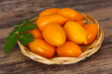 Yellow tomato heap in the wooden bowl