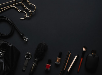 Accessories for women's beauty. Make up brush,watch,perfume bottle,hanger,wallet,nail polish, comb,belt all on a black background with top view and copy space.  Minimal black 2020 trends Flat lay.