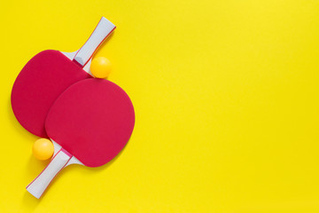 Red tennis ping pong rackets and orange balls isolated on a yellow background, sport equipment for table tennis