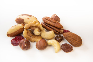 Mixed nuts and dried fruits in wooden bowl on white background, copy space