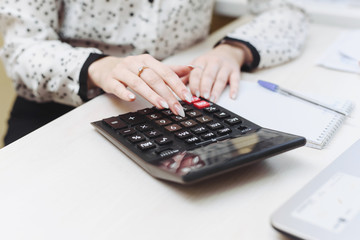 A woman considers on a calculator costs, revenues, expenses. Distribution of the family budget. Businesswomen is engaged in accounting