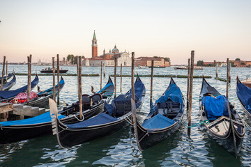 Fototapeta na wymiar Gondolas moored by Saint Mark square with San Giorgio di Maggiore church, Venice