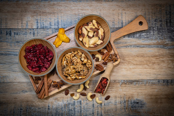 Mixed nuts and dried fruits in wooden bowl on wood background, copy space