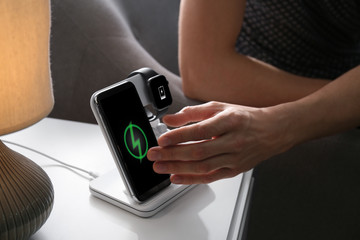 Man taking smartphone from wireless charger in room, closeup