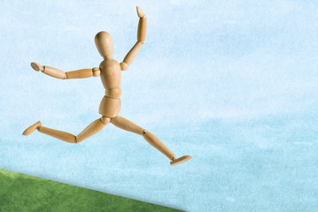 wooden mannequin on a blue watercolor background in a pose of a running man