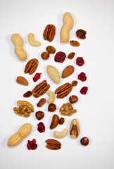 Mixed nuts and dried fruits in wooden bowl on white background, copy space