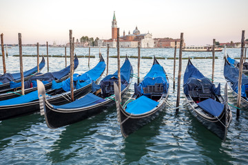 Fototapeta na wymiar Gondolas moored by Saint Mark square with San Giorgio di Maggiore church, Venice