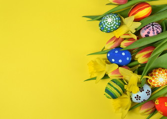 Happy Easter - painted eggs and daffodils on colored background