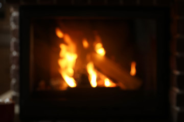 Blurred view of fireplace with burning wood indoors