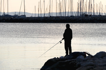 Silhouette of an unrecognizable fisherman on the beach in Split, Croatia.