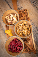 Mixed nuts and dried fruits in wooden bowl on wood background, copy space