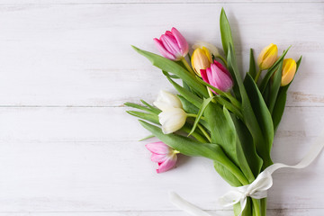 Bouquet of colorful tulips on white wooden background