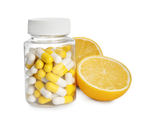 Bottle with vitamin pills and lemon on white background