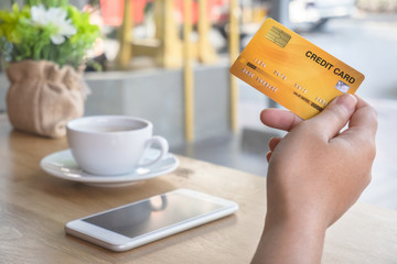 Woman holding credit card in coffee shop. Warm tone.