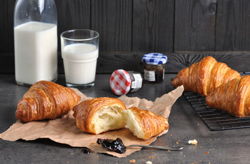 Tasty fresh croissants with jam and milk on grey table