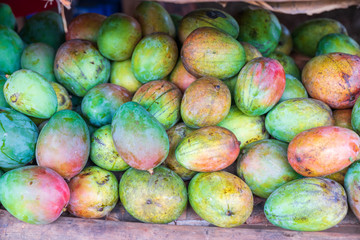 Red and green mango stack at grocery on tropical marketplace outdoor,Samana peninsula,Dominican republic.