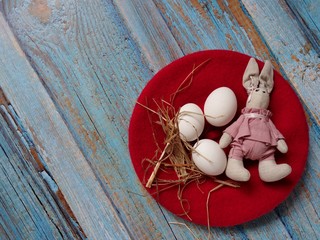 festive Easter layout of three eggs in a straw basket with a rabbit on a colored background