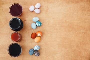 Obraz na płótnie Canvas Natural dye easter eggs on wooden table with copy space. Pink eggs - with beetroot, turquoise - red cabbage, orange and yellow - onion or turmeric, grey and purple - carcade tea. Zero waste
