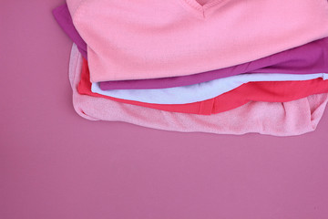 Pink folded clothes in a stack on a purple background