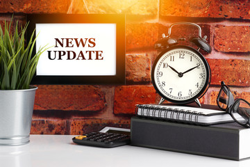 NEWS UPDATE text with alarm clock, books and vase on brick background. Business, Quotes and Copy...