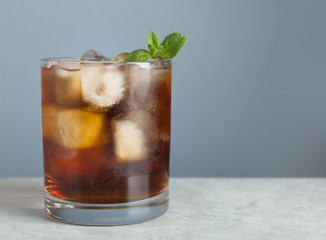 Tasty cocktail with ice cubes and mint on light marble table, closeup. Space for text