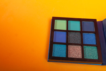 Fototapeta premium Eye shadow palette with blue colors on yellow background. Make up concept. Copy space image for your text
