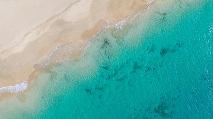 Fototapeta na wymiar Top View on Coast of Atlantic Ocean, waves on beach aerial view, crystal clear water in Morro Jable Fuerteventura. 