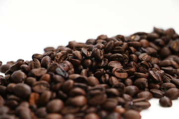 An isolated pile of roasted coffee beans on a white background surface