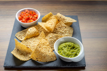 Mexican Nachos tortillas with two sauces to eat, guacamole and chopped tomatoes with parsley