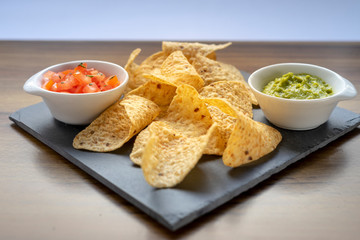 Mexican Nachos tortillas with two sauces to eat, guacamole and chopped tomatoes with parsley