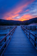Biscuit basin walkway with blue steamy water and beautiful colorful sunset. Yellowstone, Wyoming, USA