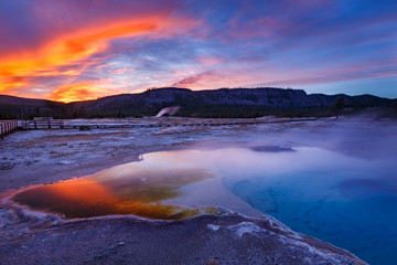 Obraz na płótnie Canvas Sapphire Pool in Biscuit basin with blue steamy water and beautiful colorful sunset. Yellowstone, Wyoming, USA