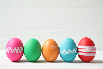 Colorful Easter eggs on white wooden background. Space for text