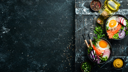 Buddha bowl: egg, green peas, onion, radish and carrots in a black stone bowl.
